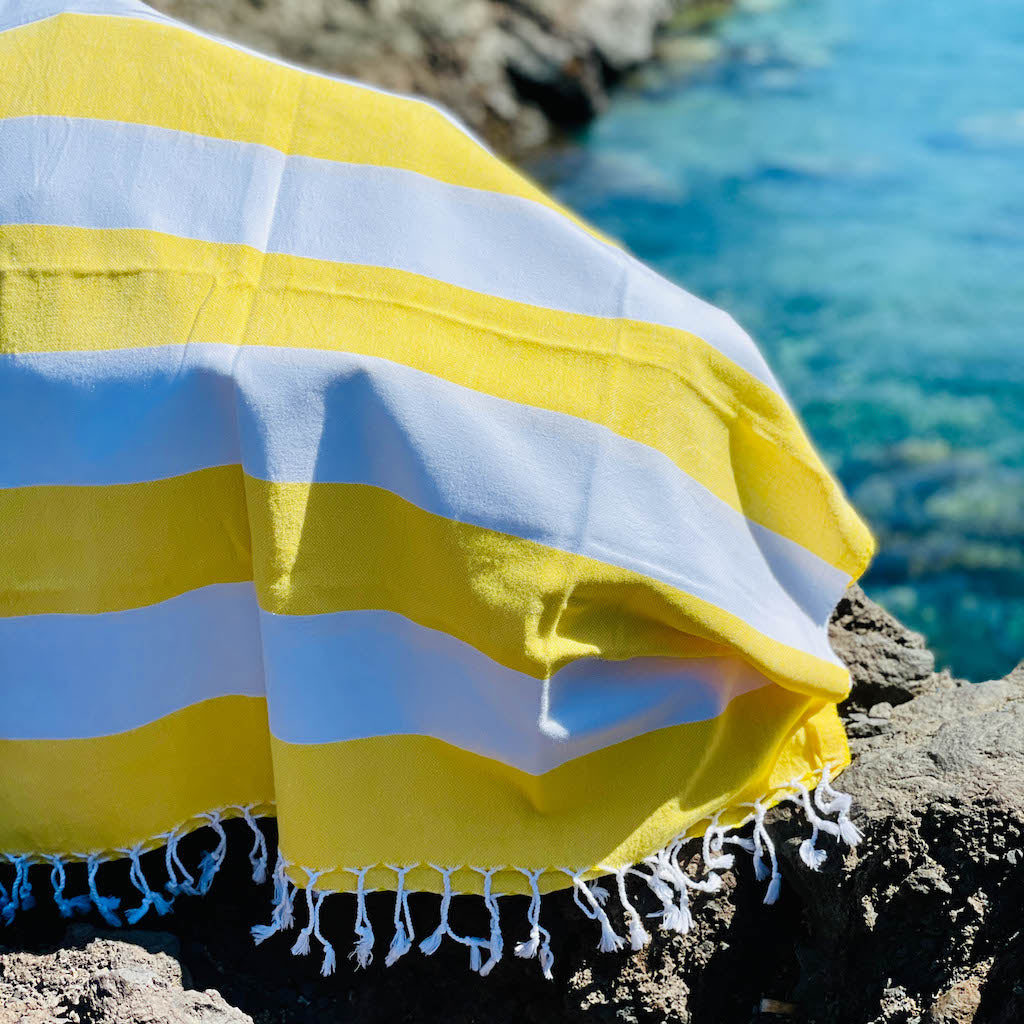 sunshine yellow bold hammam towel draped over rocks