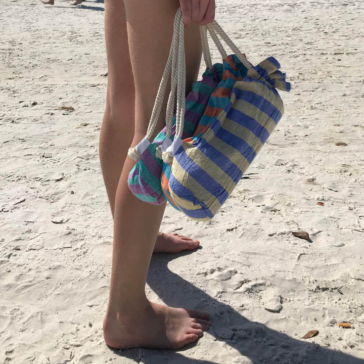 girl carrying hammam towels in bags on beach 