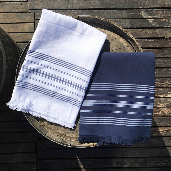 small white and navy dina terry backed towels on wooden barrel