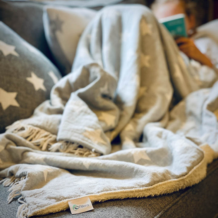 Girl reading on sofa under powder grey star fleece lined throw