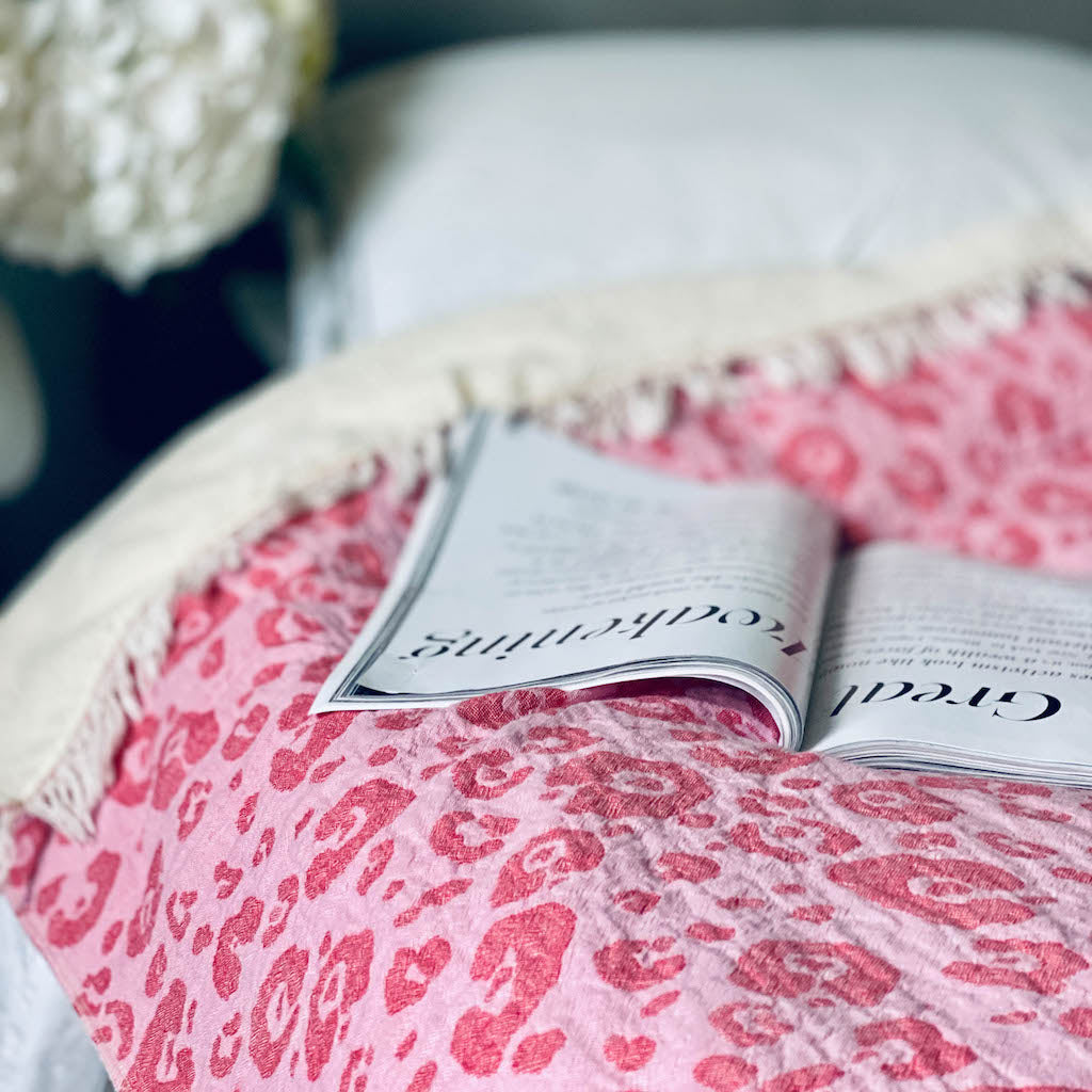 Pink leopard fleece lined throw on bed with magazine