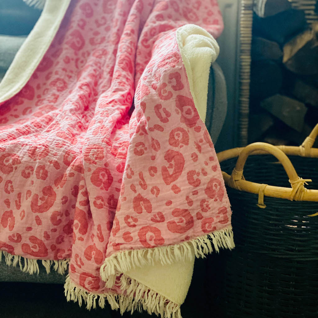 Pink leopard fleece lined throw on sofa next to log basket